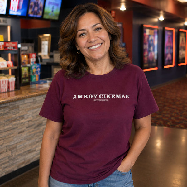 Woman holding popcorn in a movie theater lobby wearing Amboy Cinemas Sayreville NJ t-shirt