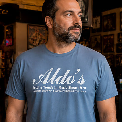 Man in front of a music memorabilia wall wearing Aldo's Hideaway Lyndhurst NJ t-shirt