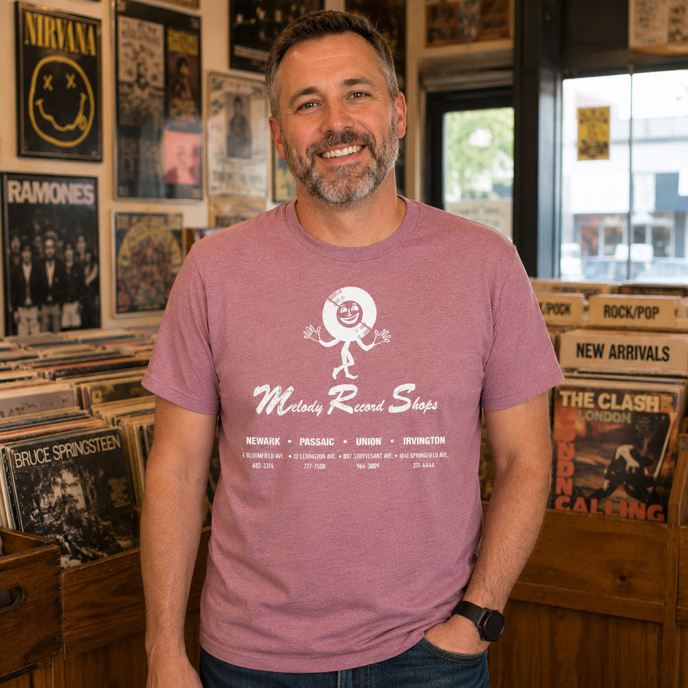 Man in a record store surrounded by vinyl wearing Melody Record Shops NJ t-shirt