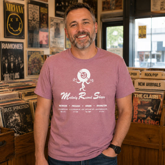 Man in a record store surrounded by vinyl wearing Melody Record Shops NJ t-shirt