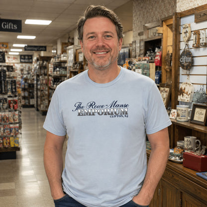 Man wearing a light blue Rowe-Manse Emporium Clifton NJ t-shirt in a classic New Jersey neighborhood emporium with vintage gift displays.